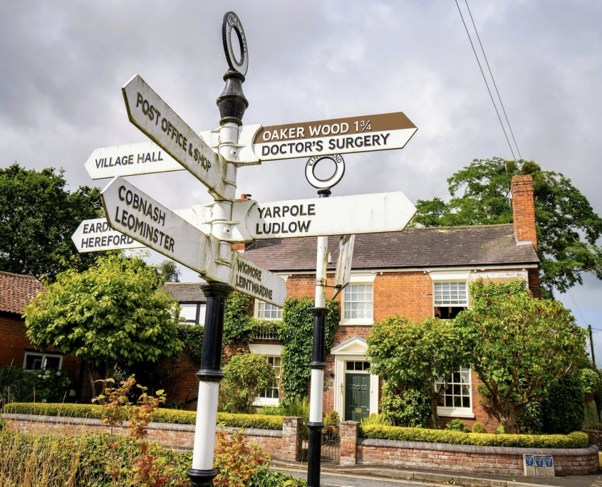 Old fashioned signpost in Kingsland village listing directions to post office, shop, doctors, Cobnash and Ludlow